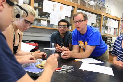 Murray Middle School science teacher Tim Chase helps eighth-grade students as they dissected frogs during one of the last days of the school year. Photo by Kristal Leebrick