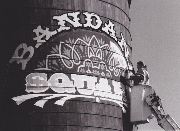 The Bandana Square logo is painted on a nearby tower in 1983. The photo, by Terry Johnson-McCaffrey, was published in the October 1983 Bugle.