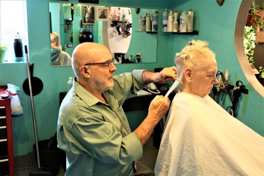 Eddie Owens, owner of the Turning Heads salon in St. Anthony Park, cuts the hair of client Cynthia Cramer. Photo by Lou Michaels. 
