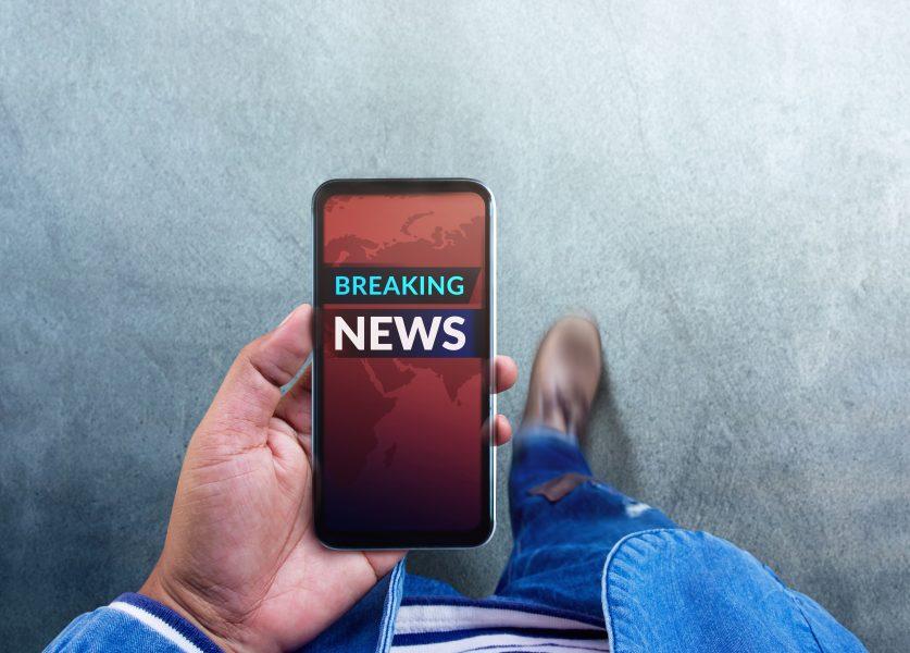 Breaking News Headline Showing on Mobile’s Screen. Person Using a Smartphone to Checking News and Update. Top View