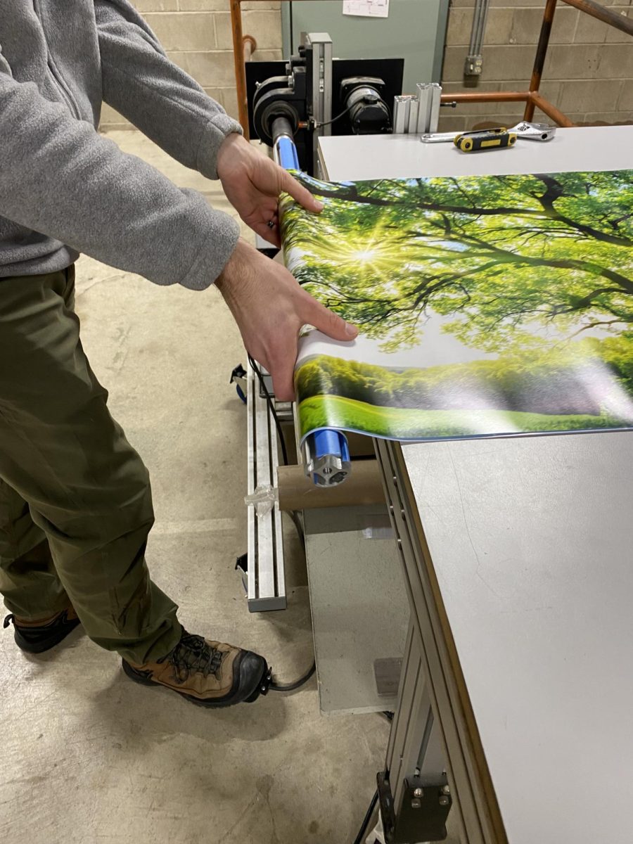 EdgeTec owner Scott Hudson shows how a rolling machine protects the edges of a poster for packaging.